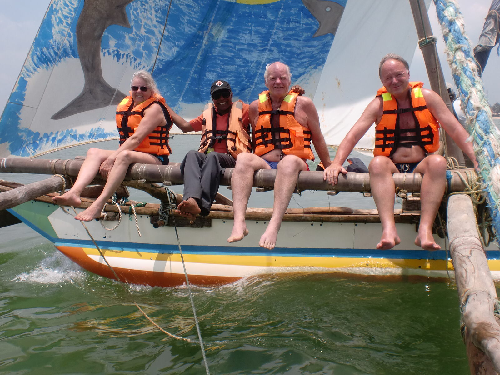 Sitting along the outrigger of a sailing boat in life jackets