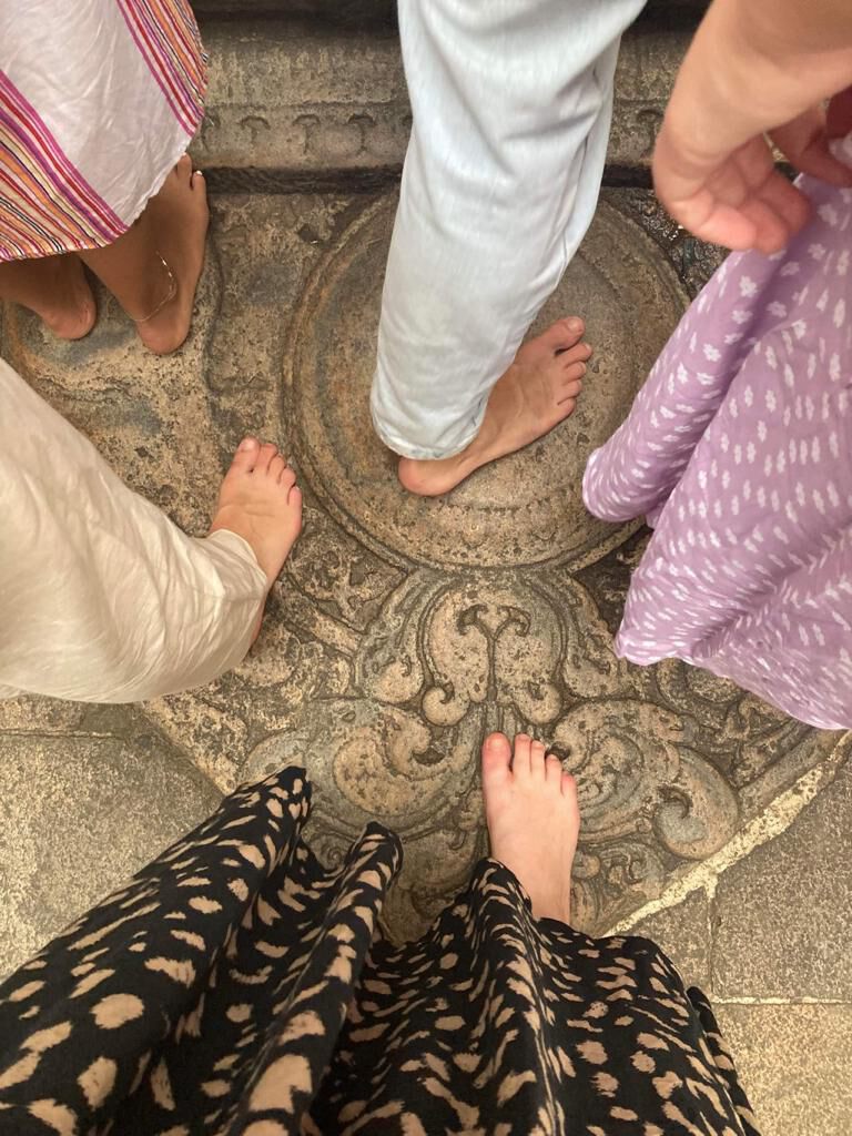 Bare feet on a carved moonstone at a temple